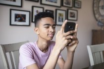 Menino adolescente usando smartphone em casa — Fotografia de Stock