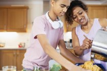 Madre e hijo adolescente cocinando en la cocina - foto de stock