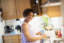 Porträt einer lächelnden, selbstbewussten Frau, die in der Küche kocht — Stockfoto