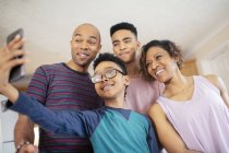 Familia sonriente tomando selfie en casa - foto de stock