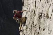 Männlicher Bergsteiger erklettert Felswand, schaut nach oben — Stockfoto