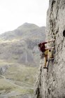 Чоловічий альпініст, що масштабує обличчя каменю, дивлячись вниз — стокове фото