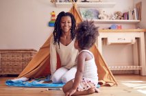 Mother and daughter playing on bedroom floor — Stock Photo