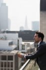 Nachdenklicher Geschäftsmann auf sonnigem, urbanem Balkon — Stockfoto