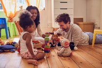 Молодая семья играет с игрушками на полу — стоковое фото