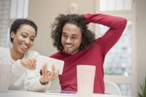 Casal feliz usando smartphone na mesa — Fotografia de Stock