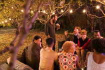 Друзья разговаривают и пьют на вечеринке в саду — стоковое фото