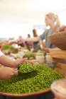 Woman scooping shelled peas at farmers market — Stock Photo
