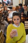 Mujer joven preocupada usando el teléfono inteligente en la cafetería - foto de stock
