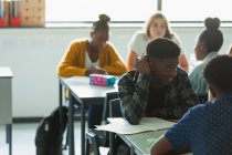 Gymnasiasten machen Hausaufgaben und reden an Tischen im Klassenzimmer — Stockfoto