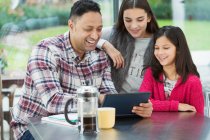 Pai feliz e filhas usando tablet digital na cozinha da manhã — Fotografia de Stock