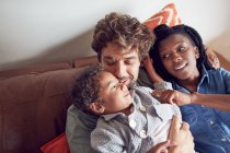 Affectionate young family cuddling on sofa — Stock Photo