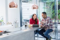 Couple using digital tablet at kitchen island — Stock Photo
