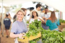 Retrato sorrindo, mulher confiante trabalhando, transportando caixa de legumes no mercado de agricultores — Fotografia de Stock