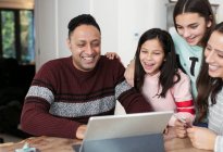 Щаслива сім'я використовує цифровий планшет за столом — стокове фото