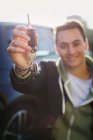 Retrato joven feliz sosteniendo llaves de coche nuevas con llavero en forma de corazón - foto de stock