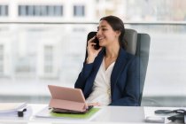 Femme d'affaires souriante parlant sur le téléphone intelligent dans le bureau — Photo de stock