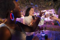 Счастливые молодые женщины-друзья пьют коктейли на заднем дворе — стоковое фото