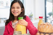 Menina sorrindo retrato com suco de laranja na cozinha — Fotografia de Stock