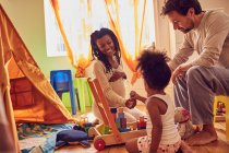 Schwangere junge Familie spielt mit Spielzeug — Stockfoto