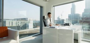 Geschäftsmann arbeitet in sonnigem, urbanem Büro — Stockfoto