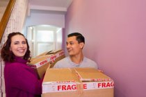 Portrait heureux couple déménagement maison, portant des boîtes en carton dans le couloir — Photo de stock
