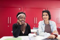 Portrait confident, smiling female community college students with paperwork in classroom — Stock Photo