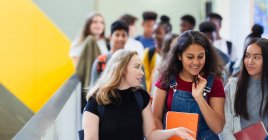 Студентки средней школы ходят и разговаривают в коридоре — стоковое фото
