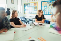 Gymnasiasten reden und lernen am Tisch im Klassenzimmer — Stockfoto