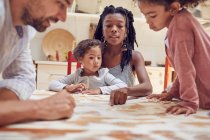 Junge Familie spielt Scrabble-Wortspiel am Tisch — Stockfoto