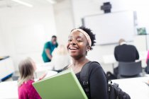 Porträt glückliche, selbstbewusste Studentin mit Bindemittel im Klassenzimmer — Stockfoto