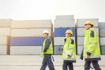 Hafenarbeiter gehen auf Werft an Frachtcontainern entlang — Stockfoto