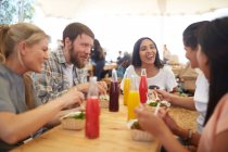 Smiling friends enjoying lunch at farmers market — Stock Photo