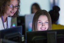 Жінка молодший викладач допомагає студенту за комп'ютером в комп'ютерній лабораторії — стокове фото