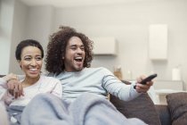 Happy couple relaxing, watching TV on living room sofa — Stock Photo