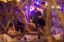 Друзья разговаривают и пьют на вечеринке в саду — стоковое фото