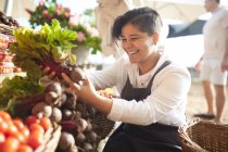 Lächelnde junge Frau arbeitet, sortiert Produkte auf Bauernmarkt — Stockfoto
