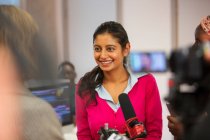 Smiling, confident female community college journalism student behind microphone — Stock Photo