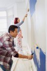 Couple painting wall with paint rollers — Stock Photo