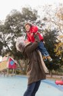 Бабуся піднімає онуку на дитячому майданчику — стокове фото