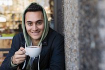 Портрет усміхнений, впевнений молодий чоловік п'є каву в тротуарному кафе — стокове фото