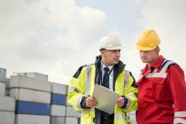 Dock worker and manager with clipboard talking at shipyard — Stock Photo