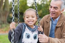 Giocoso nonno e nipote su altalena parco giochi — Foto stock