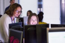 Female junior high teacher helping girl student at computer in computer lab — Stock Photo