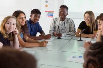 Des lycéens souriants écoutent en classe de débat — Photo de stock