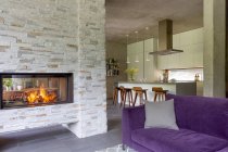 Moderno salón con chimenea de ladrillo abierto a la cocina - foto de stock