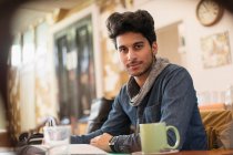 Retrato confiante jovem estudante universitário do sexo masculino estudando no café — Fotografia de Stock