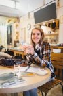 Portrait confiant jeune étudiante qui boit du café et étudie dans un café — Photo de stock