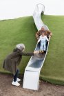 Großeltern mit Enkelin auf Spielplatz-Rutsche — Stockfoto