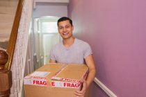 Retrato homem feliz carregando caixa em movimento no corredor — Fotografia de Stock